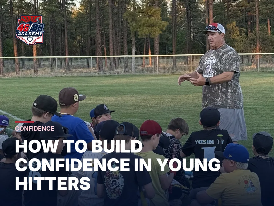 Coach talking with a seated group of young hitters at camp